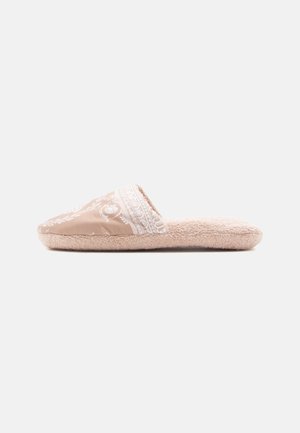 Tan fabric slipper with a textured plush sole. Decorative white pattern at the front. Open back design, rounded toe, and soft finish.