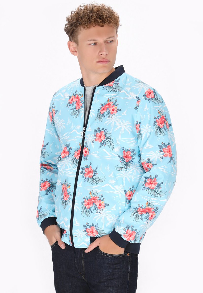 Blauwe bloemige bomberjack met roze bloemen en bladerenpatronen; ritsluiting, ribgebreide manchetten en zoom, lichte stof.