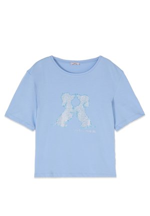 Vaaleansininen lyhythihainen t-paita, jonka etupuolella kaksi valkoista koiraa katsovat toisiaan. Kuva on tehty pienistä kimaltavista helmistä.