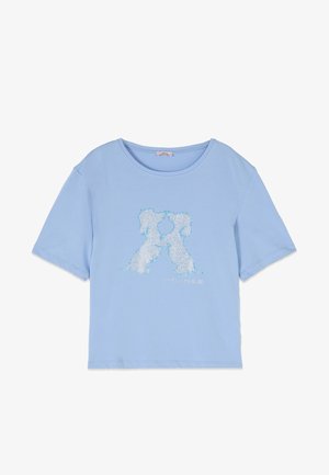 Hellblaues T-Shirt mit kurzen Ärmeln und zwei weißen Hunden, die sich auf der Vorderseite gegenüberstehen, gefertigt aus kleinen funkelnden Perlen.