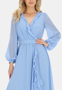 Jasnoniebieska sukienka w stylu wrap z jedwabnej tkaniny z falbanami przy dekolcie i w talii, długimi rękawami balonowymi oraz dopasowanym paskiem.