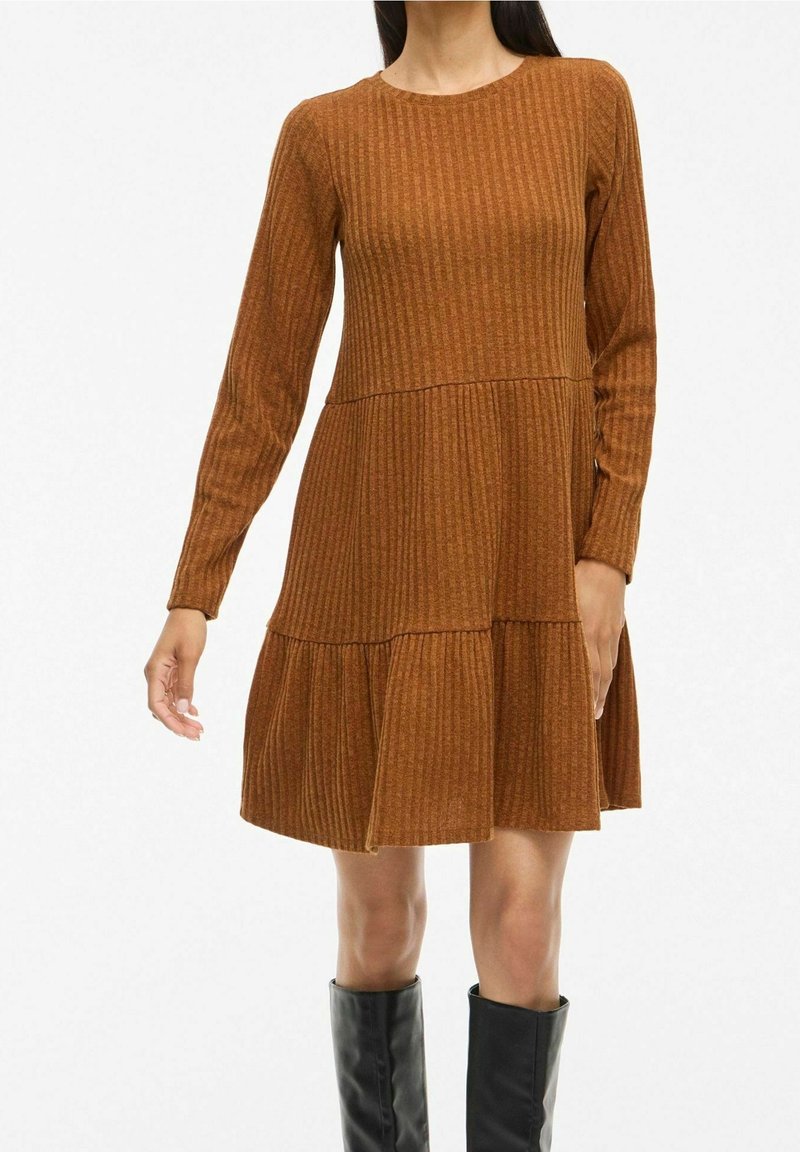 Robe marron côtelée avec manches longues, col rond et ourlet évasé à étages. Le tissu a une apparence texturée, adapté à une tenue décontractée.