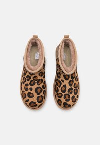 Botas de tobillo con estampado de leopardo en tonos marrón y negro, con un forro suave y acolchado. Cuentan con una lengüeta y una suela texturizada para mayor estabilidad.