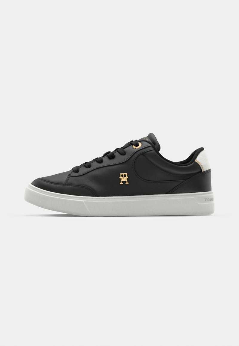 Sneaker in pelle nera con un accento bianco sul tallone, occhielli dorati e logo. Presenta una finitura testurizzata e una suola in gomma.
