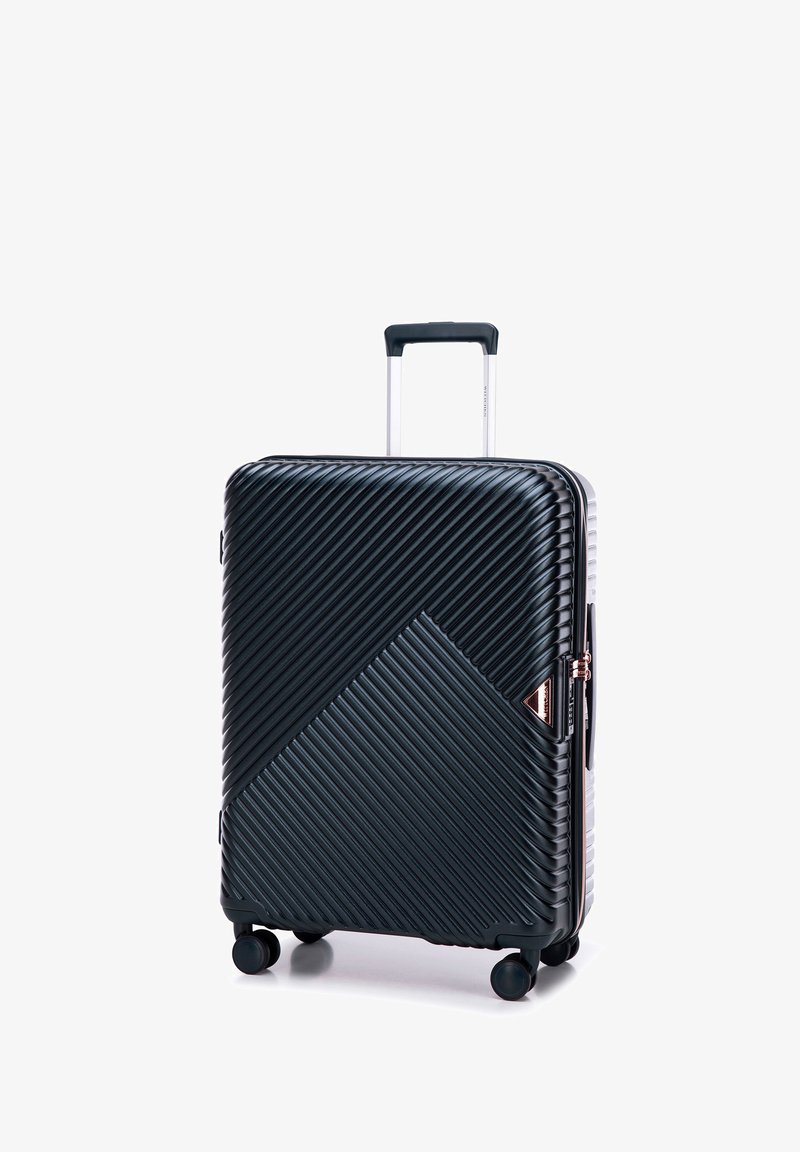 Valigia rigida nera con texture a righe diagonali, manico in argento e quattro ruote. Presenta un accento del logo triangolare e chiusura a zip.