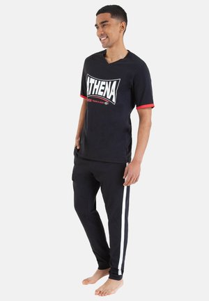 Ensemble sportif noir composé d'un t-shirt à manches courtes avec des accents rouges et un grand graphisme "ATHENA", associé à un pantalon noir avec des rayures blanches sur les côtés.
