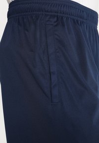 Marineblauwe sportshorts van lichtgewicht stof, met een elastische tailleband en een zijzak met een gladde textuur.