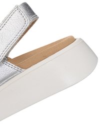 Silberne Ledersandale mit beige gepolsterter Innensohle und dicker weißer Plateausohle, ausgestattet mit einem Klettverschluss.