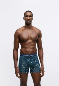 Tamsiai mėlyni bokseriai su žaliu gėlių raštu, turintys prekiniu ženklu pažymėtą elastingą juostą. Lygi tekstūra ir prigludusi forma užtikrina komfortą.