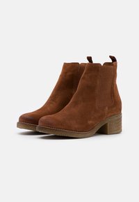 Brown suede ankle boots with elastic side panels, rounded toe, and a textured block heel. Smooth, soft texture with a simple design.