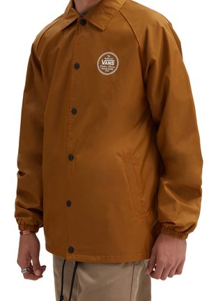 Veste légère marron à coupe décontractée, avec des boutons-pression noirs, des poignets élastiques et un logo Vans à motif écossais sur la poitrine gauche.