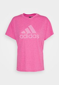 Camiseta rosa de manga corta hecha de un tejido texturizado, con un gran logo blanco de Adidas y un patrón moteado en toda la prenda.