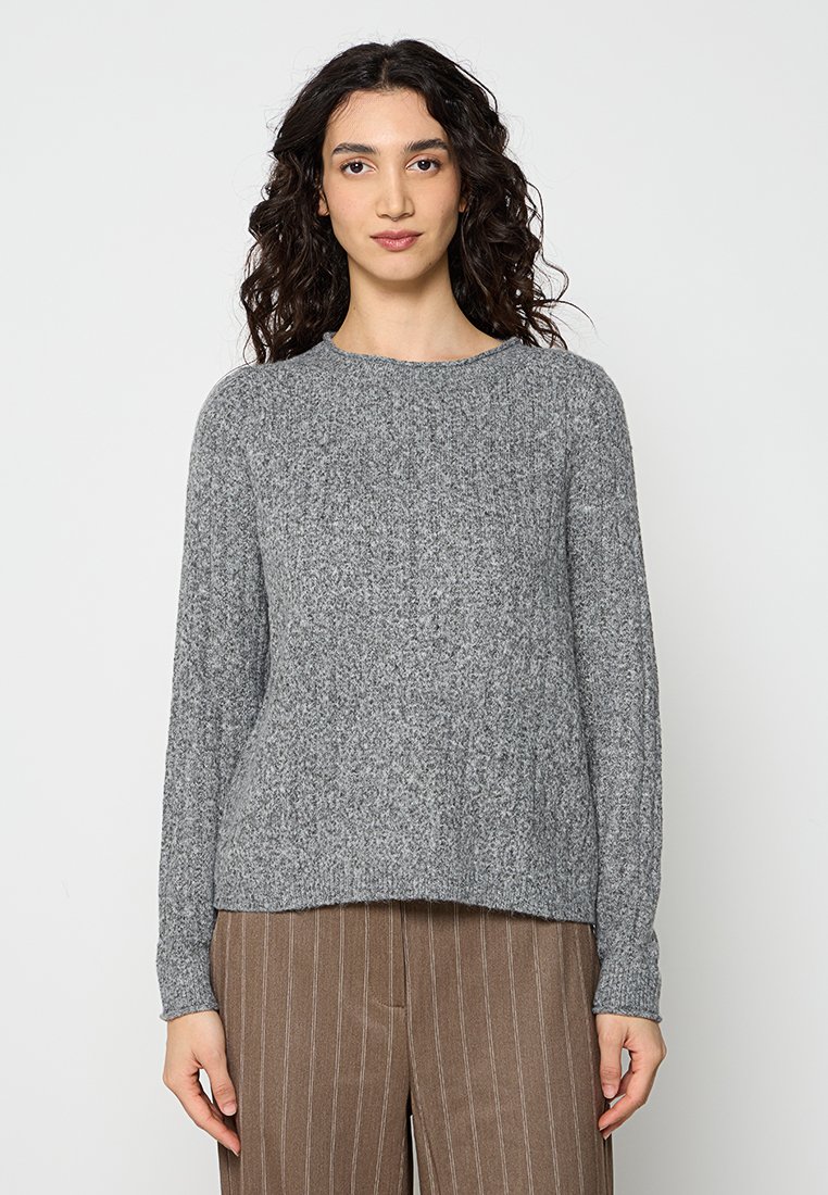 Grauer Strickpullover mit rundem Halsausschnitt, langen Ärmeln und lockerer Passform, kombiniert mit braunen Nadelstreifen-Hosen.