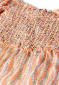 Tissu léger orange avec des vagues verticales crème et vertes. Présente une texture smockée et des bords froncés pour plus de détails.