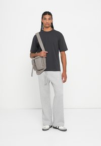 Γκρι μπλούζα, χαλαρές γκρι φόρμες και μαύρα/άσπρα αθλητικά παπούτσια. Γκρι τσάντα τύπου crossbody με δύο τσέπες με φερμουάρ. Απλό, χαλαρό ντύσιμο.