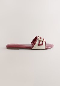Sandale plate à enfiler avec une semelle et une bride bordeaux présentant un mesh blanc et un détail de boucle dorée.