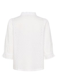Camicia bianca con texture a occhio di pernice, colletto arricciato e maniche a sbuffo. Presenta un orlo che si allarga delicatamente, aggiungendo un particolare raffinato.