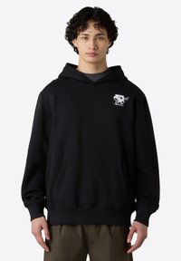 Černá mikina vyrobená z bavlněné směsi, má přední kapsu, žebrované manžety a malou grafiku na hrudi.