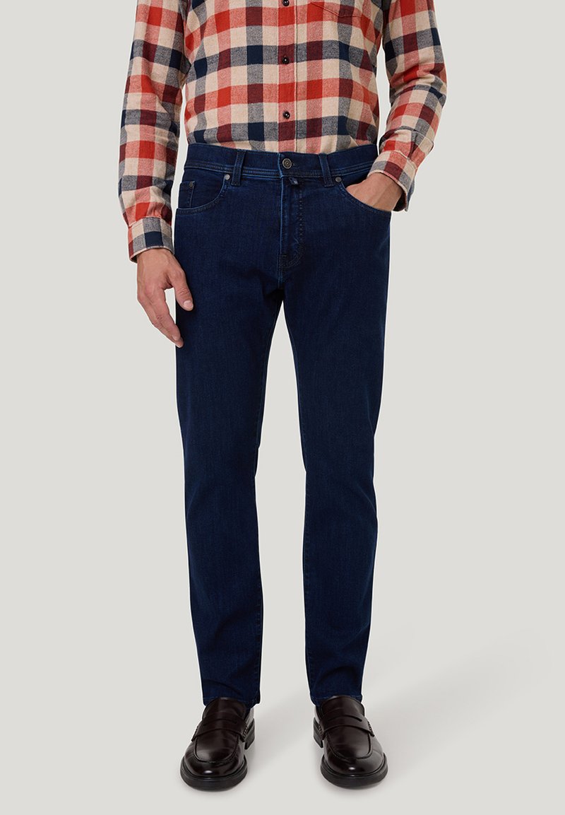 Dunkelblaue Jeans aus Denim mit schmaler Passform, kombiniert mit einem rot-blau-cremefarben karierten Flanellhemd. Glatter Stoff, minimale Details.