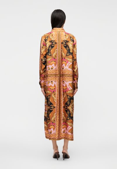 Ilga ruda suknelė su raštais ir gėlių motyvais rožinės ir juodos spalvos. Suknelėje yra apykaklė, ilgomis rankovėmis ir tiesaus silueto.