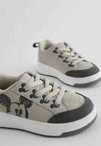 Gray sneakers with rubber soles, featuring a black toe cap and Mickey Mouse graphic on the side. Laced design with textured accents.