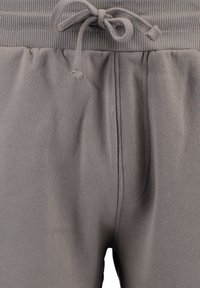Pantalones de chándal grises con cintura elástica y cordón ajustable. Fabricados en tejido suave, cuentan con bolsillos laterales y una textura lisa.
