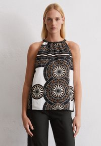Top halter negro y blanco con patrones de diseños circulares, con un escote fruncido y un ajuste holgado. Material de algodón con acentos vívidos.