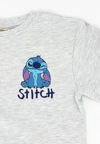 Grauer Sweatshirt mit einem Cartoon-Charakterdesign von Stitch in Blau, mit lila Akzenten, und dem Wort "STITCH" in einer fetten Schrift darunter.