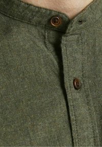 Olivgrön bomullskjorta med mandarinkrage, två bruna knappar och en strukturvävd tyg, med en ren framknäppt design.