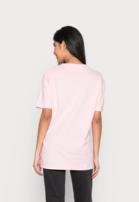 Camiseta de algodão rosa com mangas curtas, decote redondo e um corte descontraído. Textura suave, sem padrões ou detalhes visíveis.