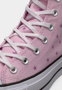 Ροζ καμβά ψηλό αθλητικό παπούτσι με λευκά κορδόνια, ασημένιες τρύπες και μικρό μοτίβο από μοβ αστεράκια. Διαθέτει λευκή λαστιχένια σόλα και ραμμένες λεπτομέρειες.