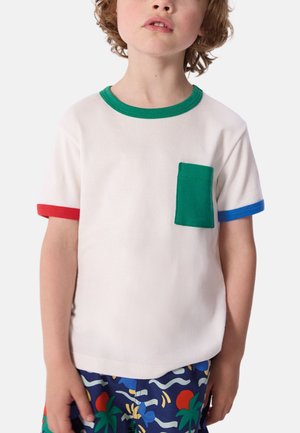 T-shirt blanc à manches courtes avec col vert, accents sur les manches rouges et bleus, et une poche poitrine verte. Texture de tissu douce et unie.