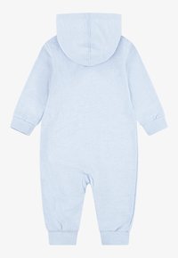 Vaaleansininen hupullinen haalari, jossa on pitkät hihat ja resorit hihansuissa. Pehmeää, teksturoitua kangasta, yksinkertaisella muotoilulla ilman näkyviä kuvioita tai korostuksia.