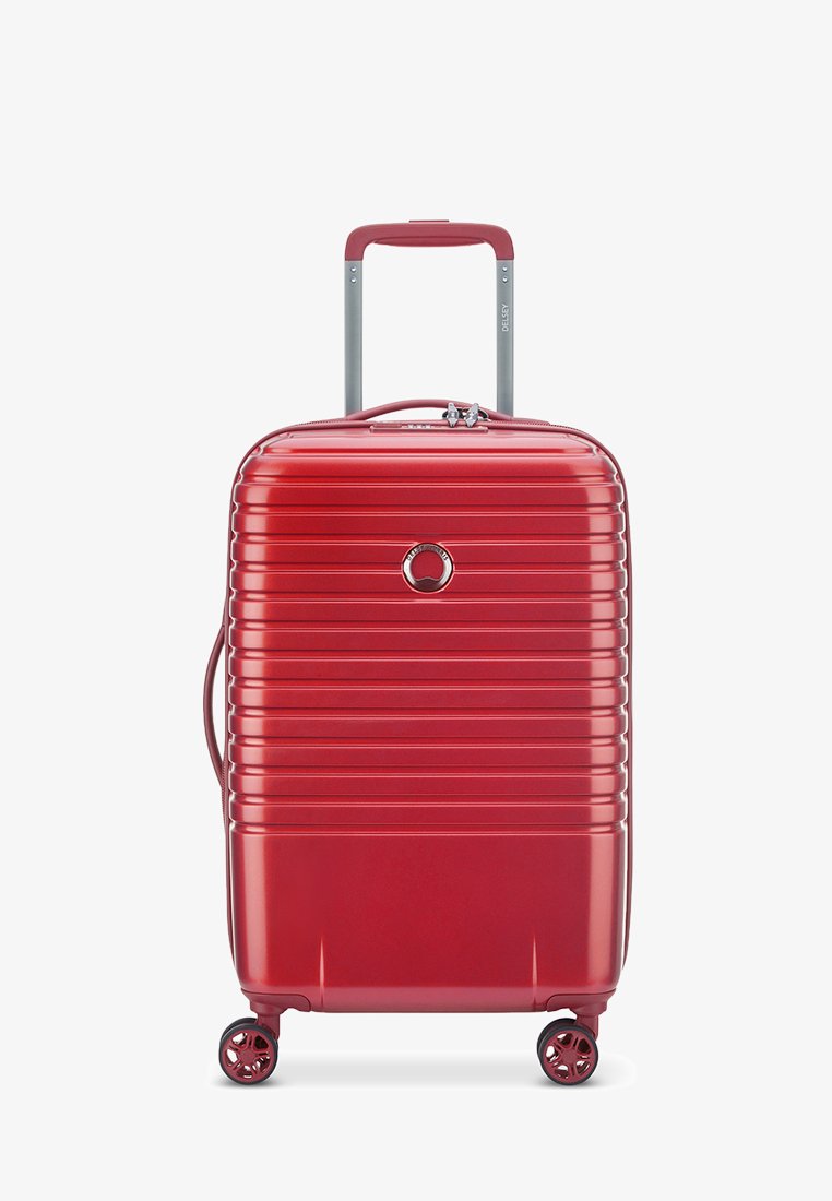 Maleta rígida roja con diseño de estrías verticales, asa extensible, cuatro ruedas giratorias y un cierre en la parte frontal.