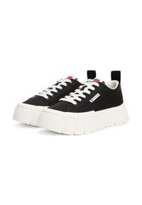 Adidași negri cu o talpă albă masivă, având o suprafață netedă, șireturi albe și un mic logo pe lateral. Talpă texturată cu caneluri.