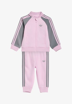 Lyserød og grå Adidas-træningsdragt til småbørn med lynlåstrøje, sidelommer, ribmanchetter og matchende bukser med sidestreger.