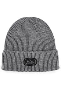 Gray knit beanie with a folded cuff, featuring ribbed texture and a black label with white logo. Soft material, casual design.