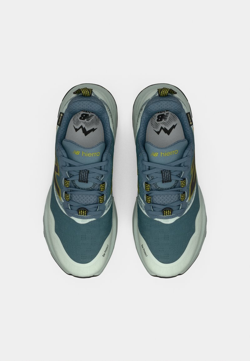 Blue and gray trail running shoes with a textured upper, prominent lacing system, and yellow accents on the tongue and side.