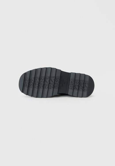 Semelle de chaussure en caoutchouc noir avec des rainures horizontales pour une traction, présentant une section texturée lisse au niveau du talon et un logo gravé près de l'arche.