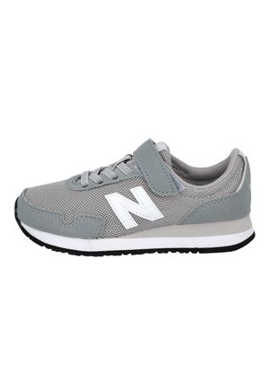 Zapatilla deportiva de malla y ante gris con logo blanco de New Balance, suela exterior negra, cordones y cierre de velcro.