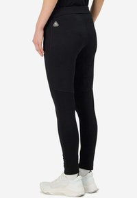 Leggings athletic neri con una texture liscia, fascia alta in vita e un accento del logo triangolare. Design aderente che arriva alla caviglia.