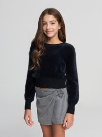 Granatowy krótki sweter o puszystej fakturze z czarnym prążkowanym ściągaczem, zestawiony z szarą spódnicą w prążki z kokardą.