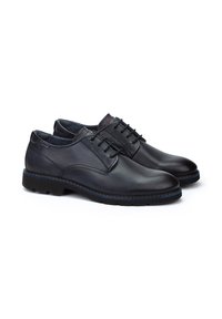 Chaussures en cuir noir avec une finition lisse, bout arrondi et accents cousus. Elles présentent un design à lacets et une bordure bleue contrastante sur la semelle.