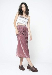 Srebrny satynowy top w stylu cropped, różowa aksamitna midi spódnica w plisach oraz ciemnobrązowe platformowe loafersy z błyszczącymi akcentami.