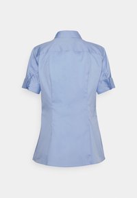 Chemise bleu clair manches courtes à boutons, avec poignets retroussés et coutures ajustées visibles de dos.