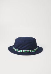 Navy blue bucket hat made of cotton, featuring a patterned white band with green and black diamond shapes around the crown.