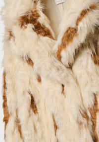 Gilet in pelliccia sintetica con toppe color avorio e marrone, caratterizzato da una texture morbida e soffice, con design frontale aperto e senza elementi di fissaggio o accessori visibili.