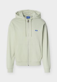 Ανοιχτό πράσινο φούτερ με φερμουάρ, μπροστινές τσέπες, κουκούλα με κορδόνι, ριμπ μανσέτες και τελείωμα, και μικρό μπλε λογότυπο "HUGO" στο στήθος.