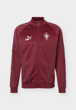 Μπορντό αθλητικό μπουφάν με φερμουάρ, μπλε διακοσμητικές ραφές, λογότυπο Puma και κείμενο "KING" στο αριστερό στήθος, έμβλημα ποδοσφαίρου Πορτογαλίας στο δεξί στήθος.