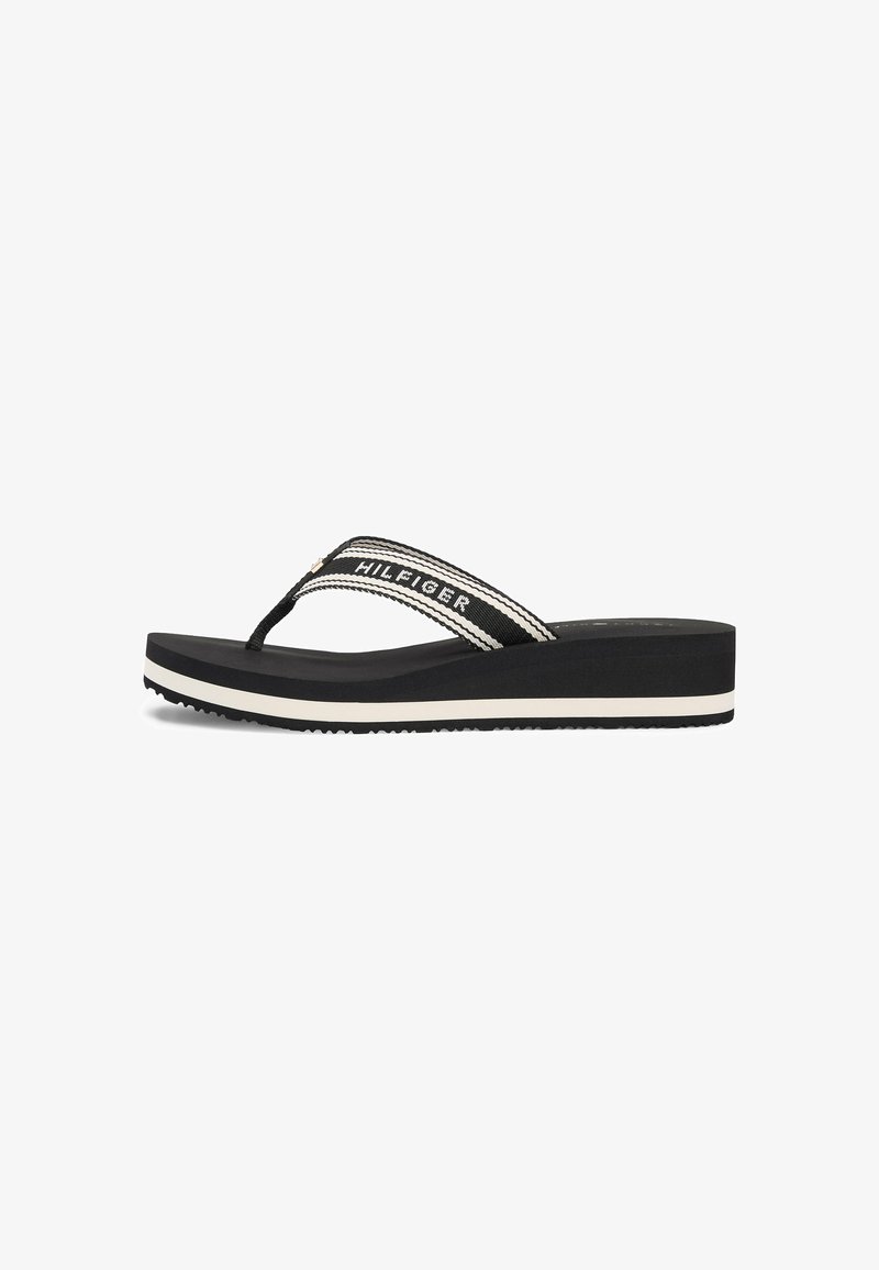 Black platform flip-flop with white stripes on sole and fabric strap featuring "HILFIGER" text in white.